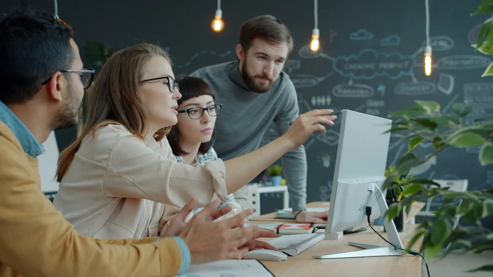 Equipe reunida em volta de um computador em um escritório